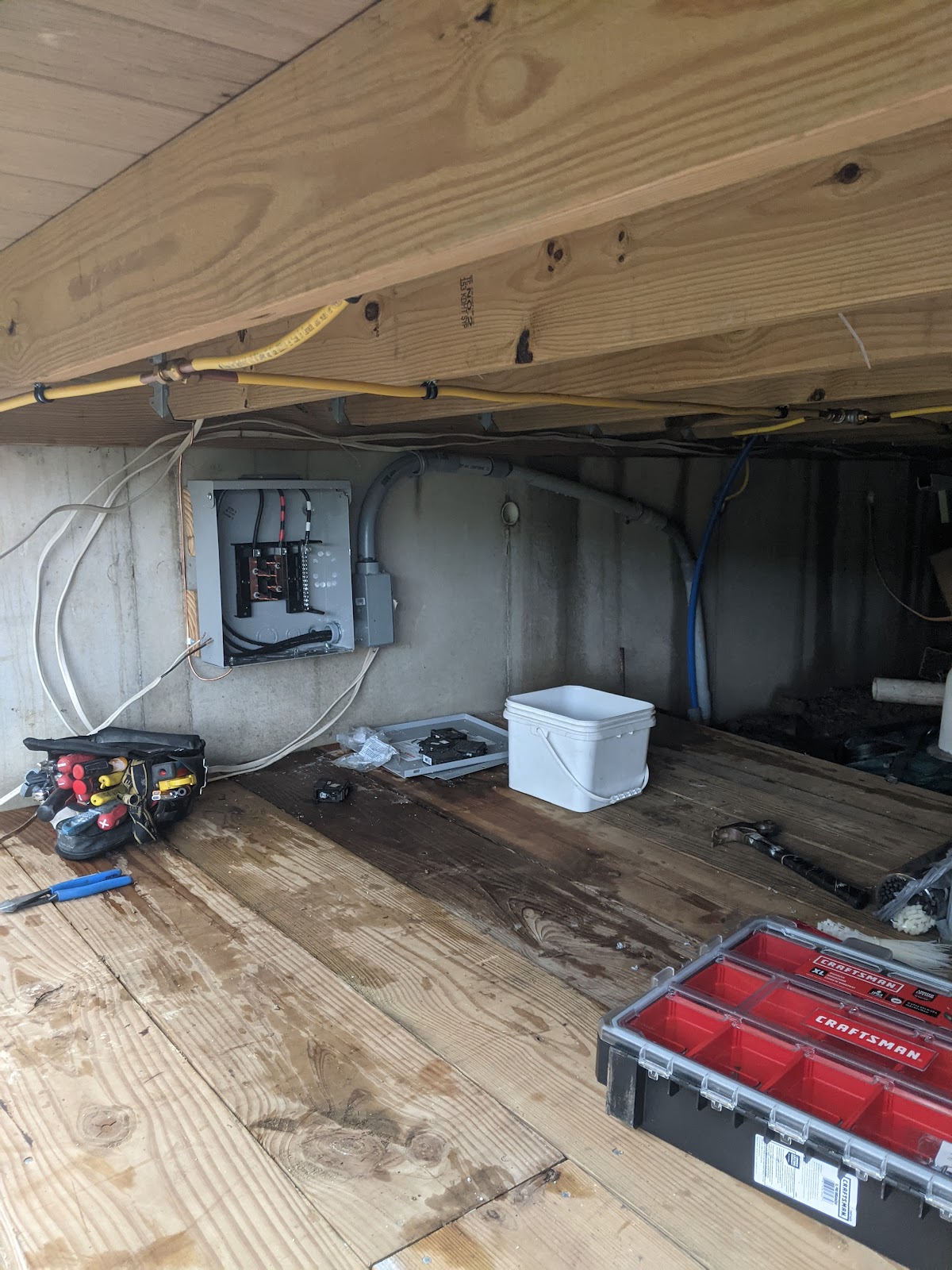 Sub-panel installation in a crawlspace with tools laid out